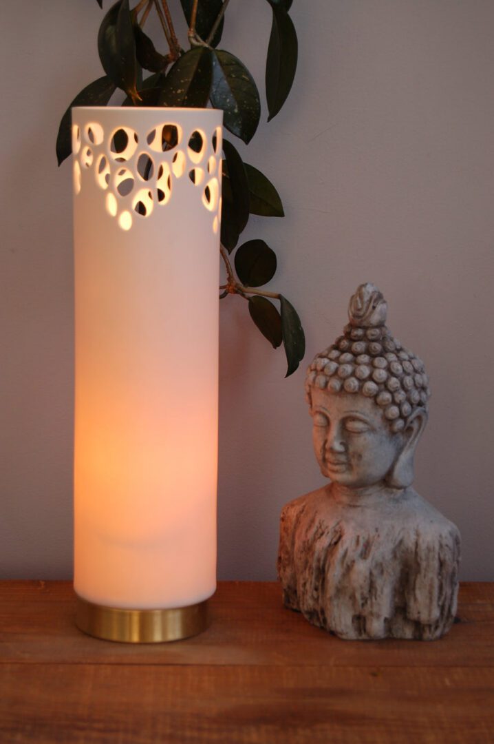 Glowing lamp beside Buddha sculpture