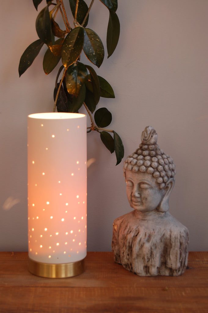 Lit cylindrical lamp beside Buddha statue