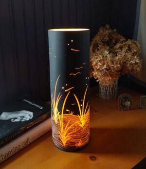 Illuminated lamp beside dried flowers