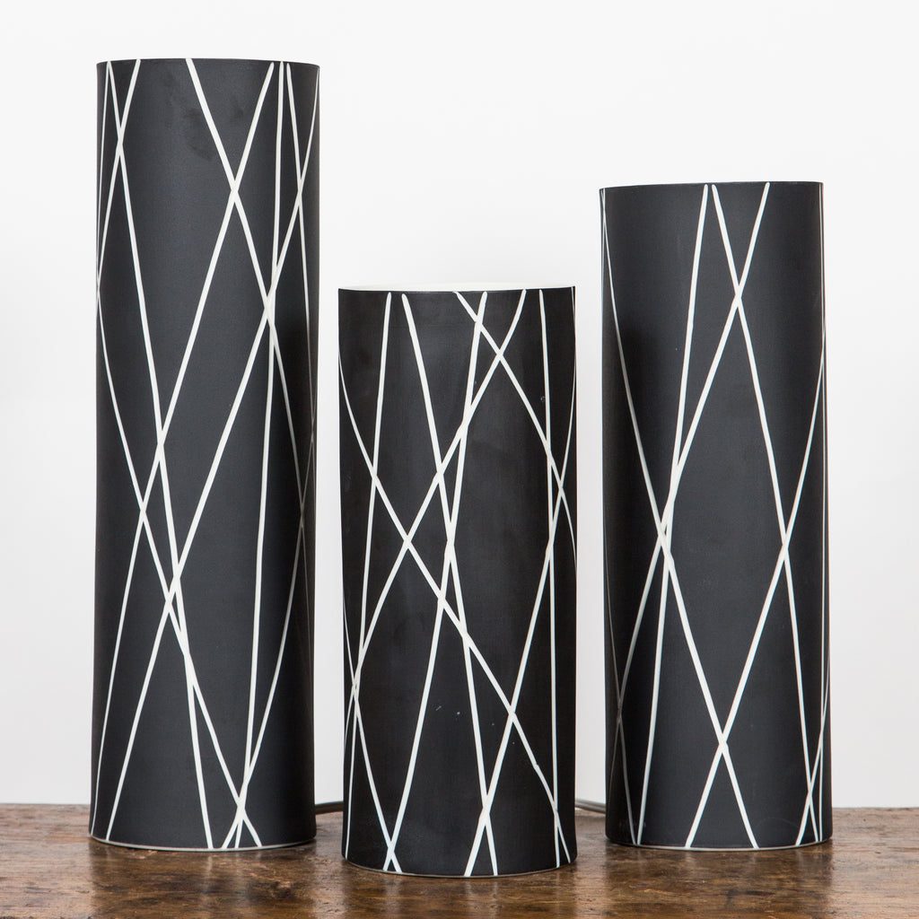 Trio of black vases with white lines.