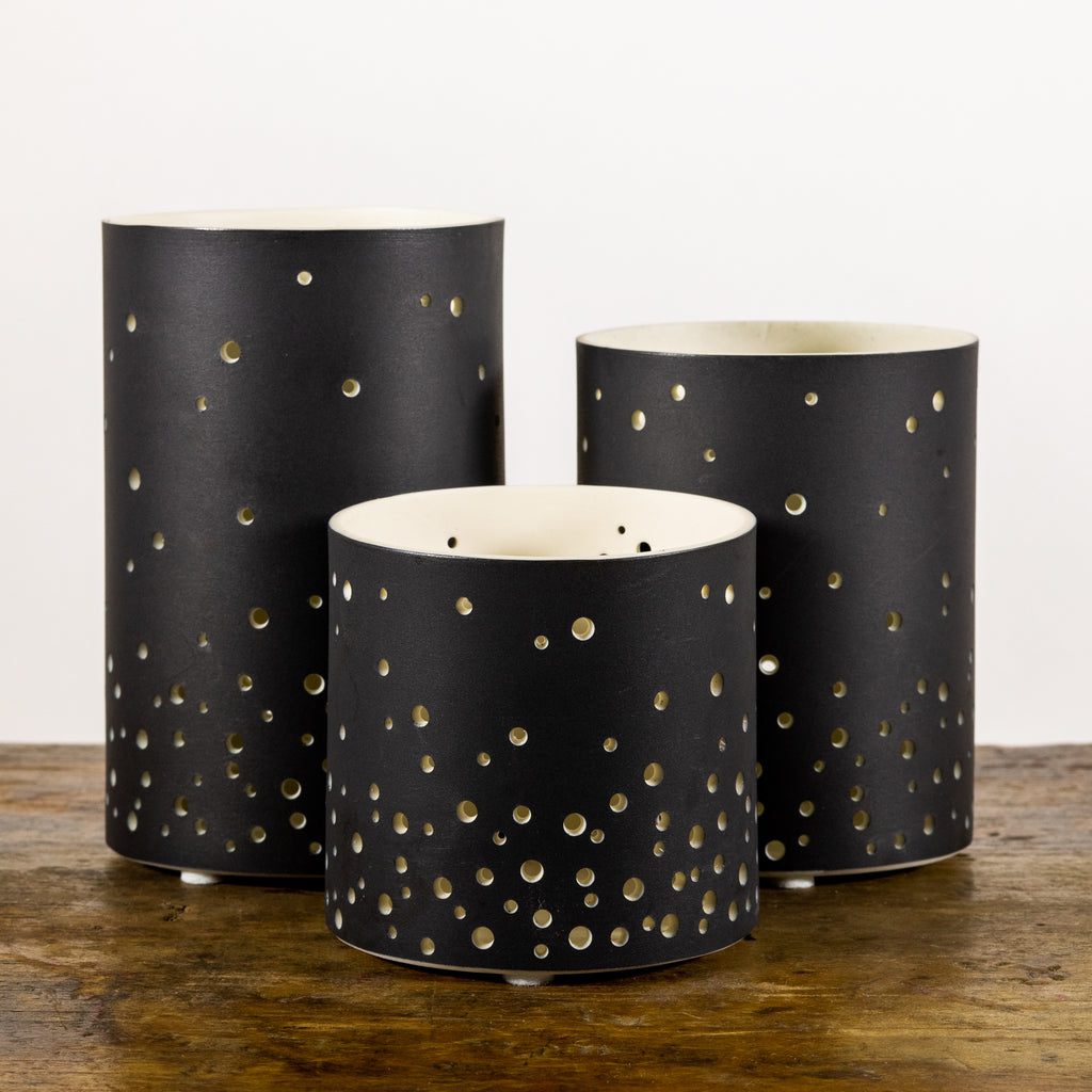 Black perforated candle holders on wood