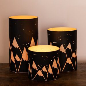 Mountain-themed candle holders on wooden table.