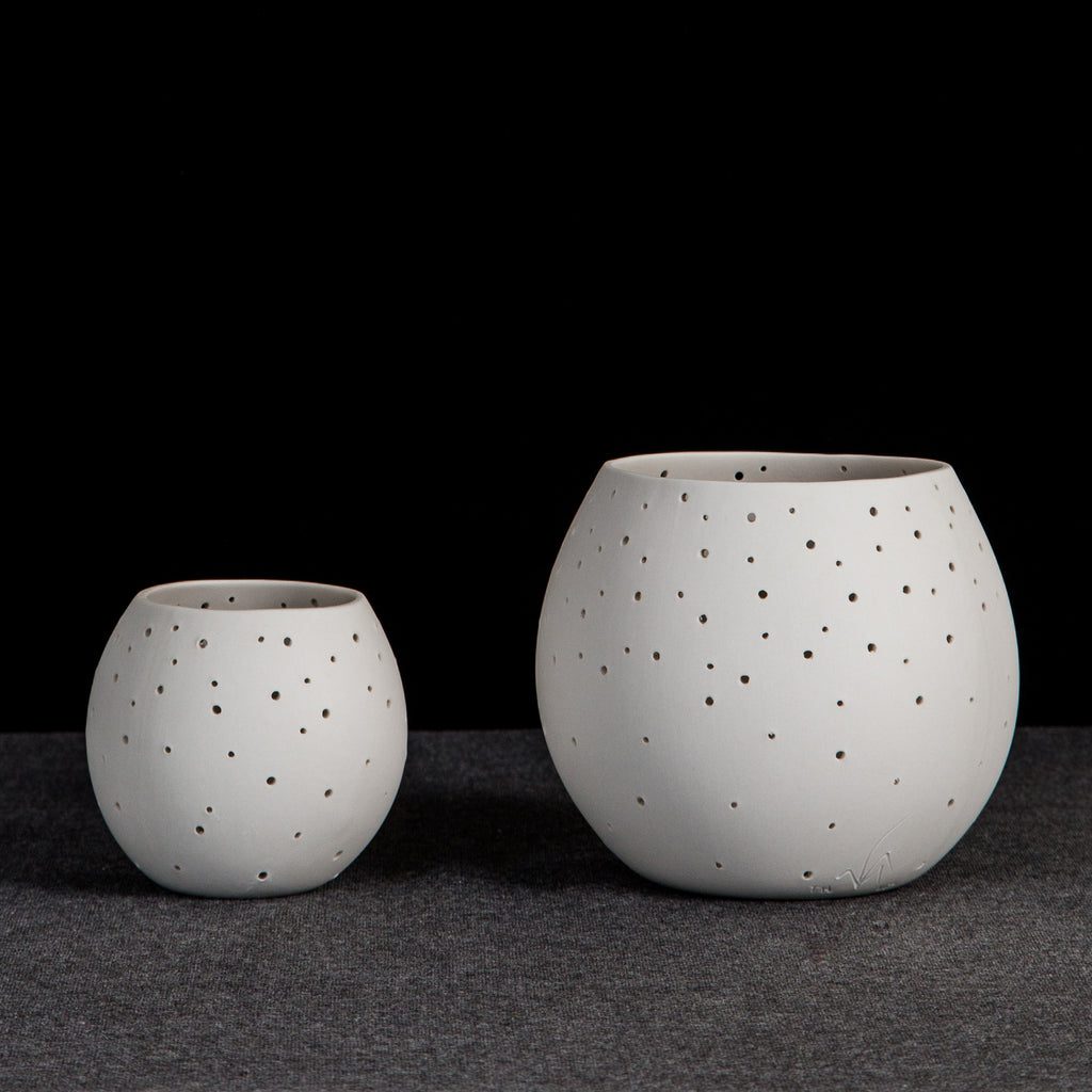 Two minimalist ceramic pots with holes.