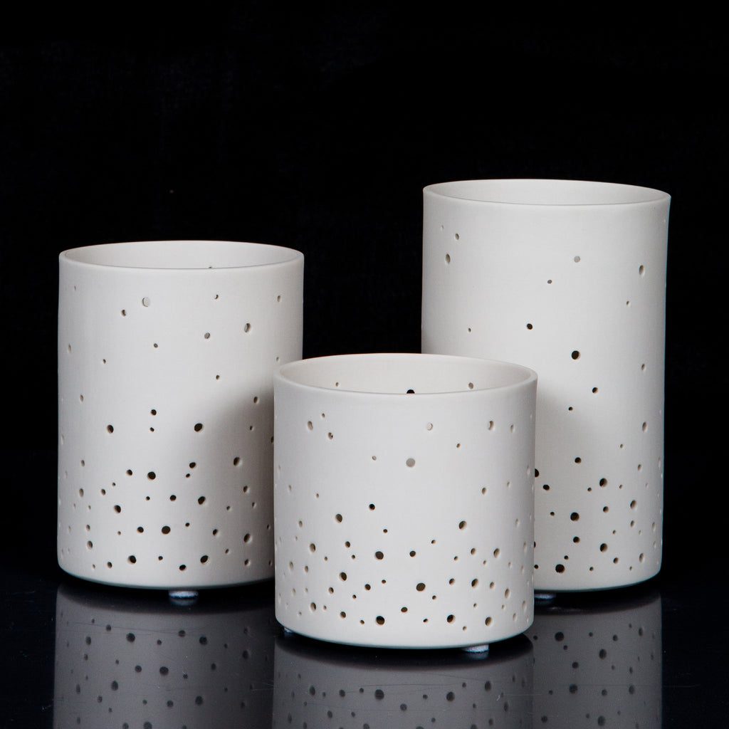 Three white perforated ceramic candle holders