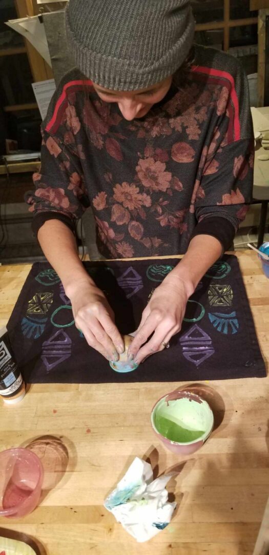 Person crafting colorful patterns on fabric table
