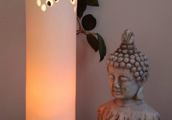Glowing lamp beside Buddha sculpture